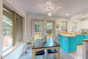 Une cuisine moderne dotée d’un îlot central, de grandes fenêtres et d’un coin repas avec des chaises.