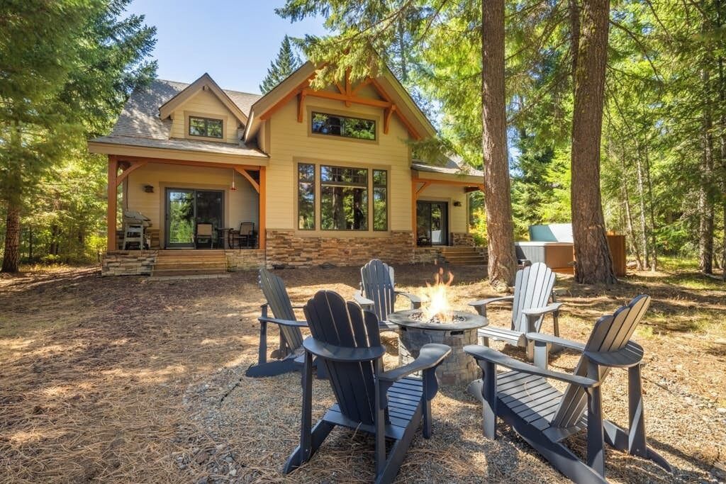 A lodge with a fire pit and Adirondack chairs in the yard.