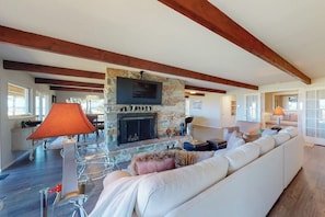 A living room with a stone fireplace, a television mounted above it, and a white sofa. - Spacious 3BR Bayview Dog Friendly - Balcony (Westport)