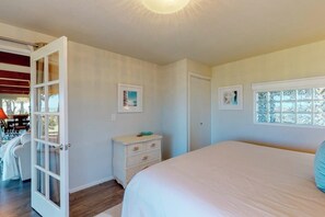 Ein Schlafzimmer mit Bett, Kommode, Tür und Fenster.