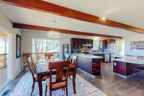A modern kitchen with wooden beams, a dining area with a chandelier, and a view of the outdoors. - Spacious 3BR Bayview Dog Friendly - Balcony (Westport)