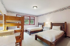 A bedroom with two single beds, a wooden desk, a chair, a nightstand, and a lamp. - 4 BR home with foosball table, gym, and large yard (Indianola)