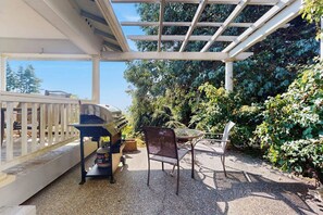 Un espacio al aire libre techado con una parrilla, una mesa y sillas.