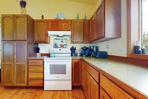 A kitchen with wooden cabinets, a white stove, and various appliances. - 3BR beachfront paradise with outstanding views (Sequim)