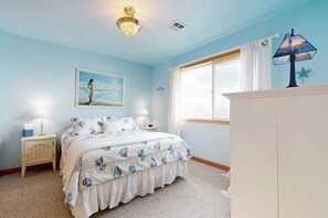 A bedroom with a bed, two bedside tables, a nightstand, a window with curtains, a lamp, and a starfish decoration. - 3BR beachfront paradise with outstanding views (Sequim)