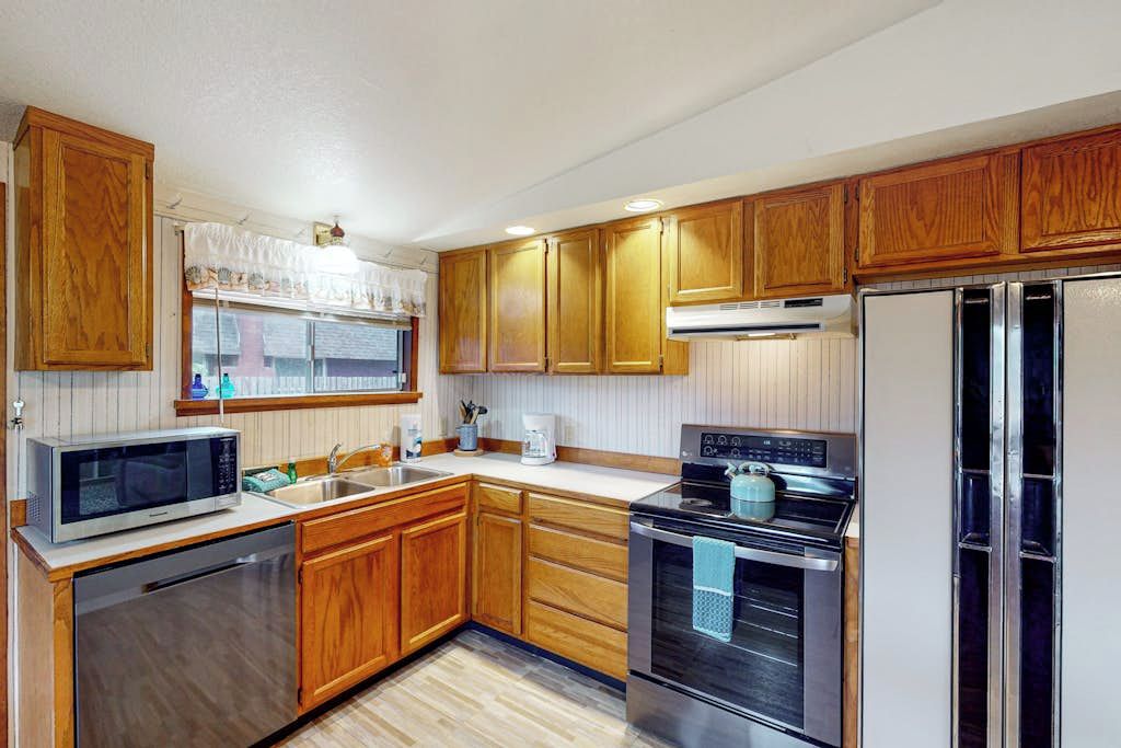 A kitchen with wooden cabinets, a microwave, a stove, and a refrigerator.