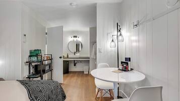 A modern kitchen with white cabinets, a round dining table, and a white chair.