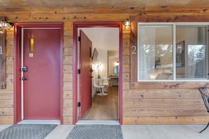 Une cabane en bois avec deux portes numérotées, un banc à l’extérieur et un intérieur visible avec une table et des chaises.
