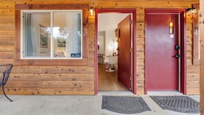 Une cabane en bois avec une porte rouge, une fenêtre avec un rideau et le chiffre « 3 » peint sur le mur.