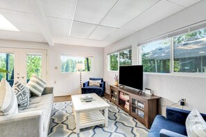 Una sala de estar con sofá, mesa de centro, televisor y aparador.