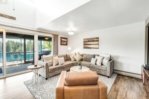 Un salon moderne avec un canapé d’angle, une table basse et une vue sur un balcon.