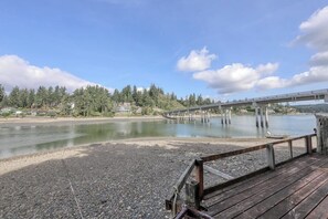 A wooden deck overlooking a calm river with a bridge in the background. - Incredible 3BR Bayview Dog Friendly - Dock (Gig Harbor)