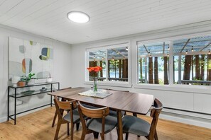 A dining area with a wooden table, chairs, and a vase of flowers. - Skiing 1BR Lakefront | Dock | Deck | Firepit (Fall City)