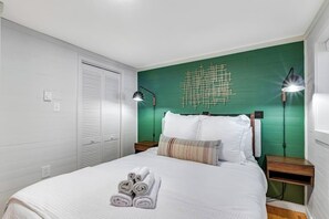 A neatly made bed with rolled towels, a green accent wall, and two bedside lamps. - Skiing 1BR Lakefront | Dock | Deck | Firepit (Fall City)