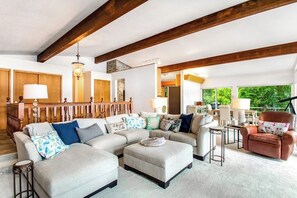 A spacious living room with a sectional sofa, ottoman, and a brown leather armchair. - 4BR Lakefront - Dock - Fireplace - Balcony (Olympia)