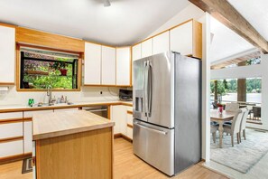 A modern kitchen with a built-in refrigerator, wooden cabinets, and a window overlooking greenery. - 4BR Lakefront - Dock - Fireplace - Balcony (Olympia)