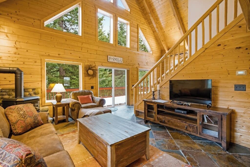 A spacious wooden interior with a fireplace, a television, and a staircase.