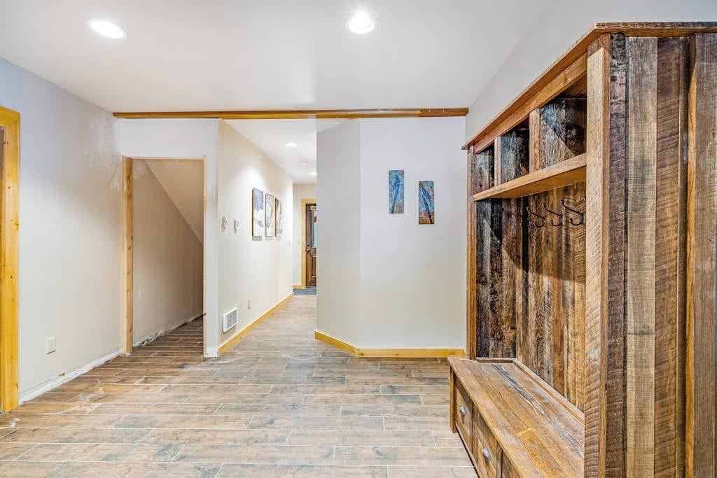 A hallway with a wooden bench, a staircase, and a wall with a rustic wooden panel.