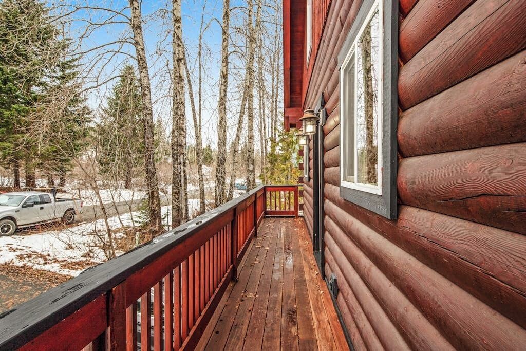 Une cabane en bois dotée d’un balcon donnant sur un paysage enneigé et des arbres.