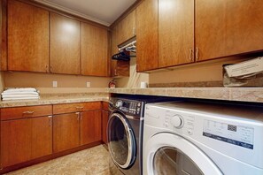 A laundry area with wooden cabinets, a washing machine, and a dryer.