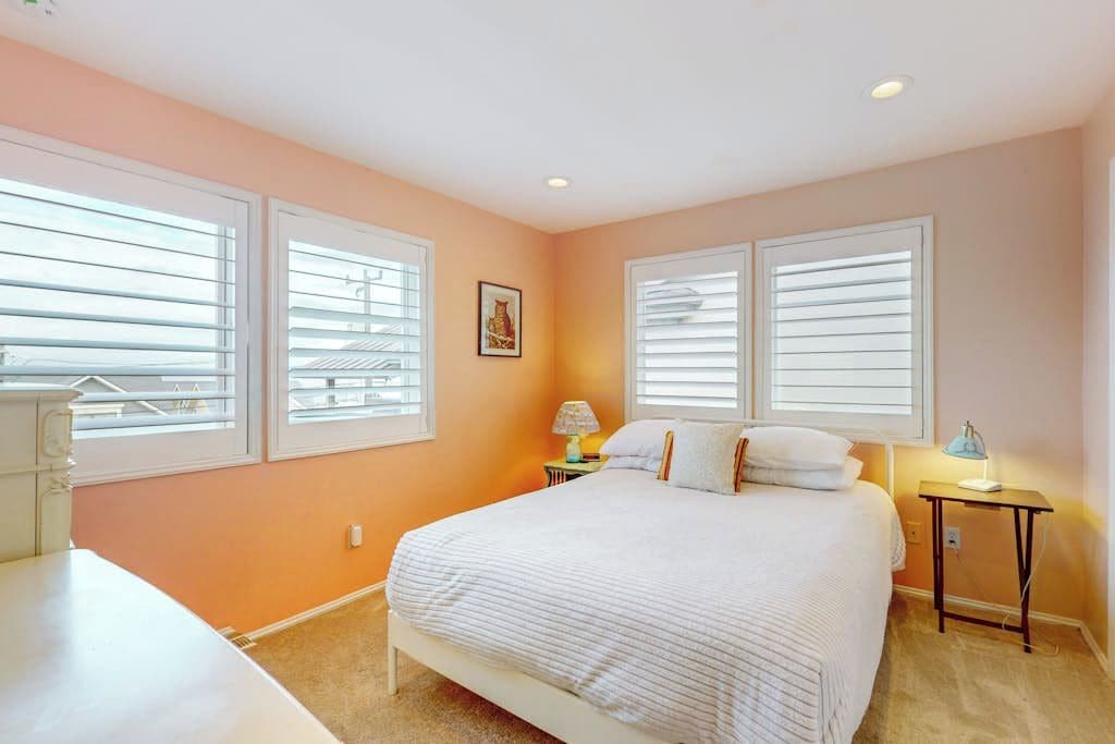 A bedroom with a bed, two bedside tables, and a window with blinds.
