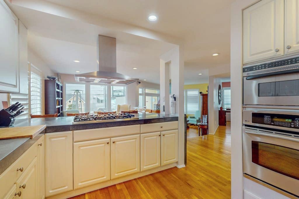 A modern kitchen with white cabinetry, a central island, and built-in appliances including a stove, oven, and microwave.