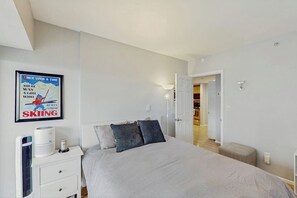 A bedroom with a bed, a radiator, a wall-mounted light, and a door leading to another room. - 1 BR downtown condo with shared pool and hot tub (Seattle)