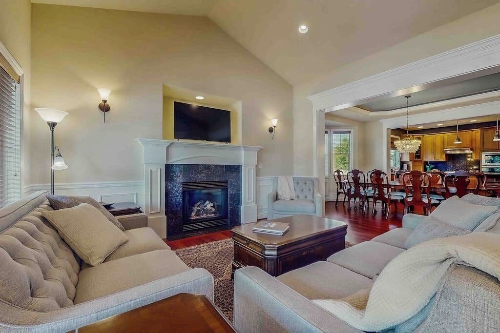 Amplia sala de estar con chimenea, asientos cómodos y vista al comedor.