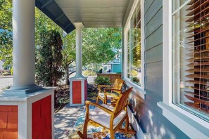 A covered porch with wooden chairs, a red and white column, and a view of the neighborhood. - 4BR Enumclaw home-AC-grill-fireplace-walk to town (Enumclaw)