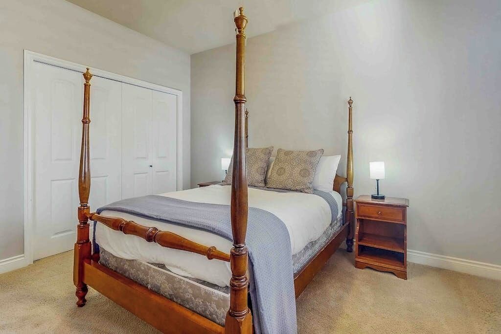 Una cama con dosel de madera y una mesita de noche a juego.