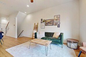 Ein Wohnzimmer mit einem grünen Sofa, einem Holztisch und einem weißen Teppich.