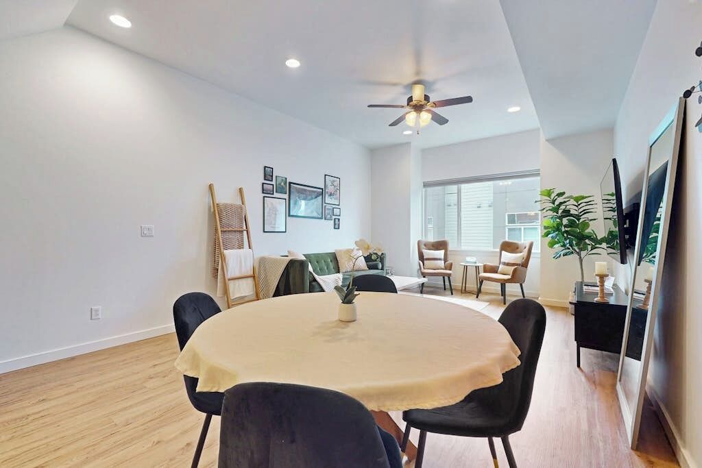 Un espace repas comprenant une table ronde, des chaises, un ventilateur de plafond et un téléviseur fixé au mur.