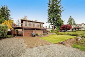A two-story house with a garage, a covered porch, and a well-maintained lawn. - Comfortable 3BR - Deck - Washer Dryer (University Place)