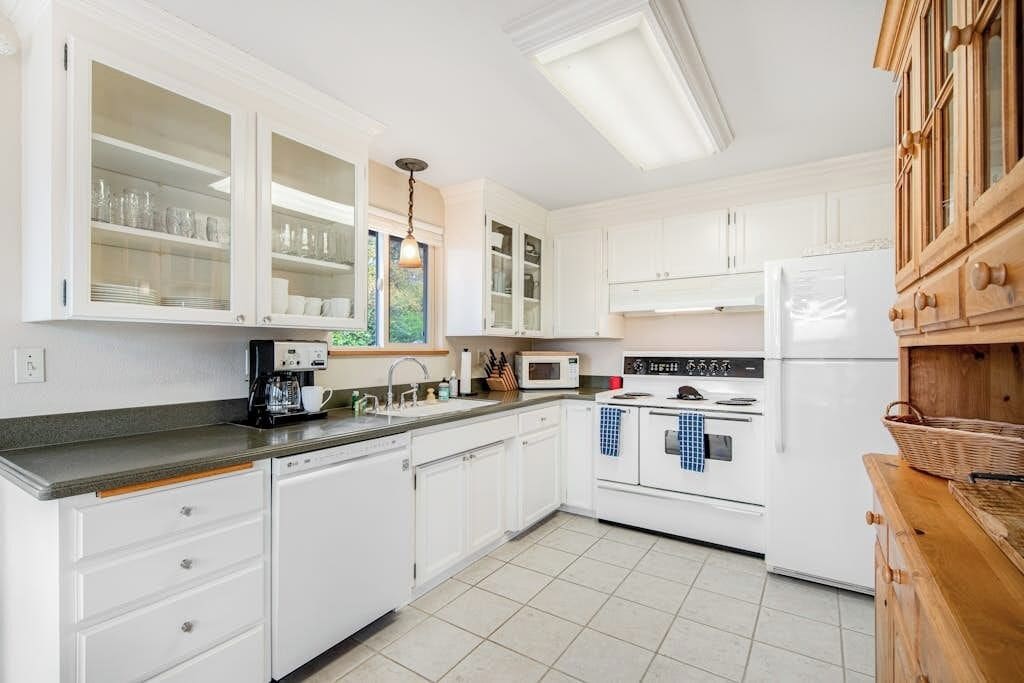 A kitchen with white cabinets, a microwave, an oven, and a sink.