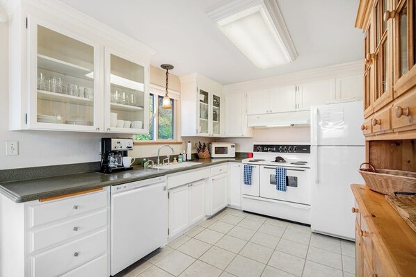 A kitchen with white cabinets, a microwave, an oven, and a sink. - Comfortable 3BR - Deck - Washer Dryer (University Place)