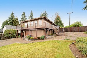 A two-story house with a covered porch and a fenced backyard. - Comfortable 3BR - Deck - Washer Dryer (University Place)