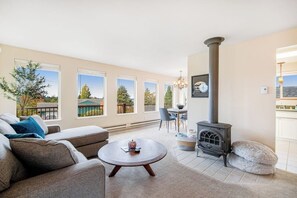 A living room with a sofa, a round coffee table, a fireplace, and a dining area with chairs and a table. - Comfortable 3BR - Deck - Washer Dryer (University Place)