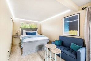 A bedroom with a bed, a sofa, a small table, and a picture on the wall. - Comfortable 3BR - Deck - Washer Dryer (University Place)