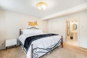 A bedroom with a bed, bedside table, and a door leading to a bathroom. - Comfortable 3BR - Deck - Washer Dryer (University Place)