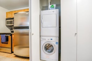 A compact kitchen with a stainless steel refrigerator, microwave, oven, and a stacked washer and dryer unit. - Amazing 1BR Washington State Conv. Center Dog Frie (Seattle)