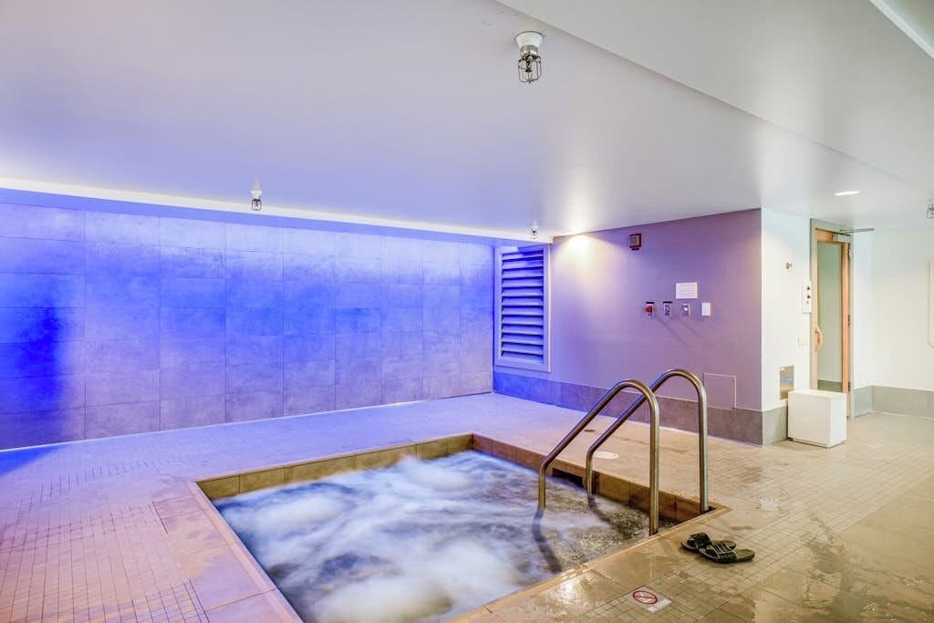 A spa area with a hot tub, a shower, and a tiled floor.