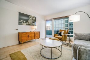 A modern living room with a round coffee table, a sofa, a chair, a cabinet, and a large window with a view of buildings. - Amazing 1BR Washington State Conv. Center Dog Frie (Seattle)