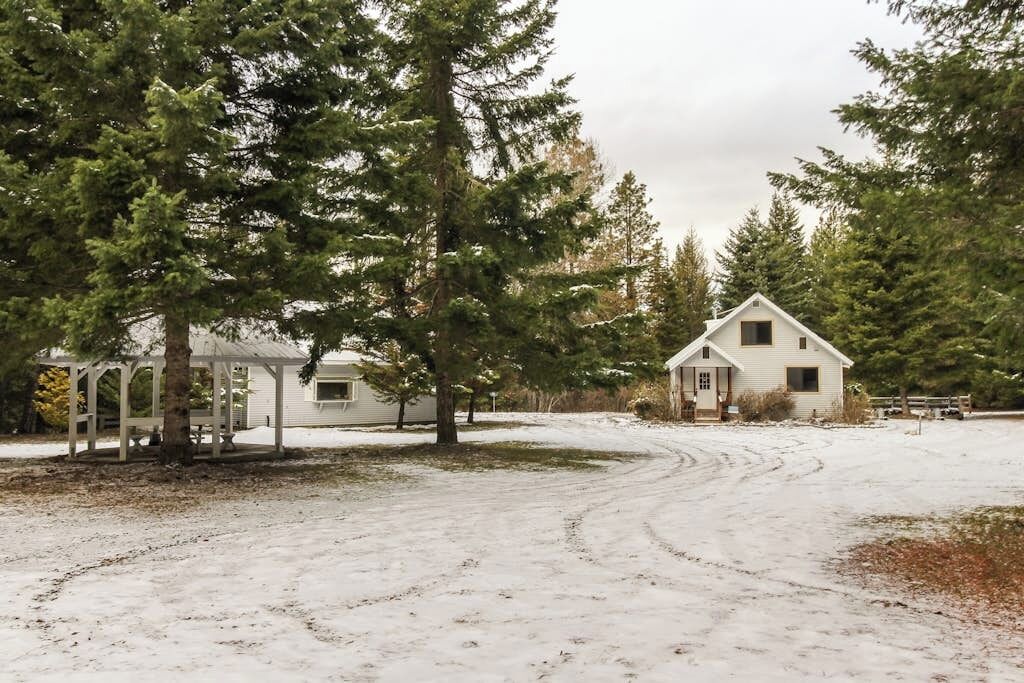 Paisagem nevada com uma casa branca e um coreto.