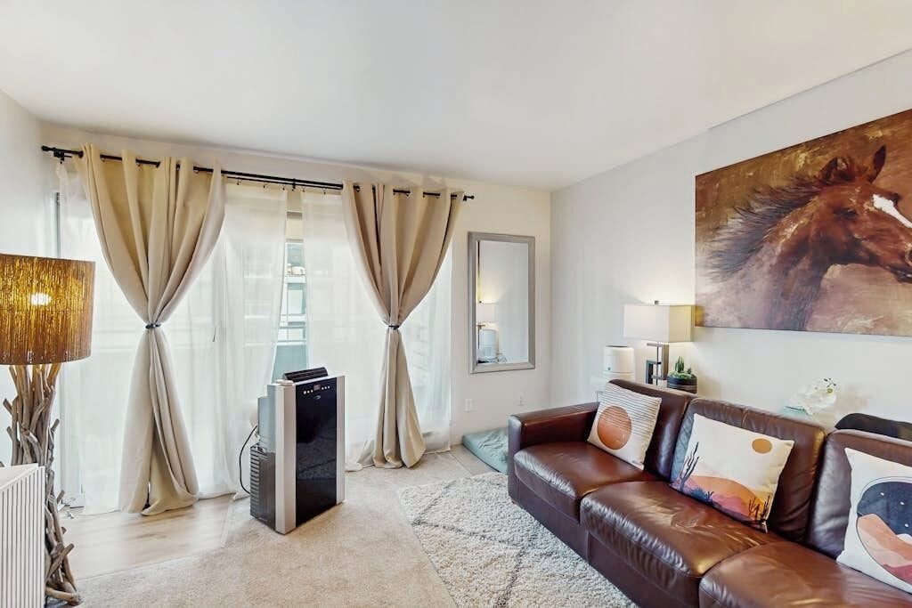 A living room with a leather sofa, a large painting, and a radiator.
