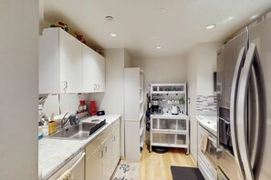 A compact kitchen with white cabinets, stainless steel appliances, and a small countertop. - 1 BR condo with shared hot tub, downtown access (Seattle)