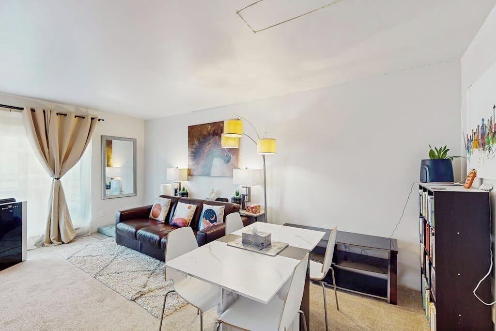 Una sala de estar moderna con un sofá, una mesa de comedor, una lámpara y una estantería.