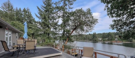 A deck with outdoor furniture overlooking a lake, surrounded by trees.