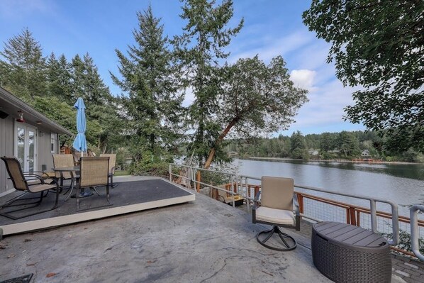 A deck with outdoor furniture overlooking a lake, surrounded by trees.