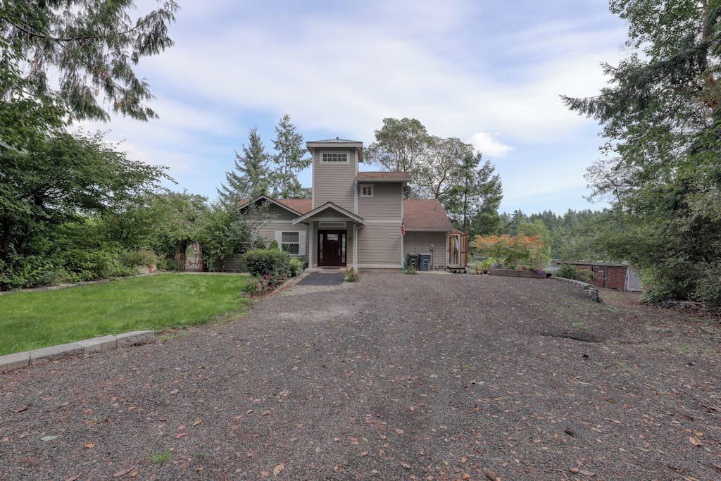 A two-story house with a front porch, a garage, and a driveway leading to the entrance.