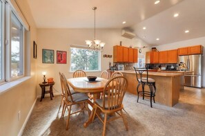 A modern kitchen with wooden cabinets, a central island, and a dining area with chairs.